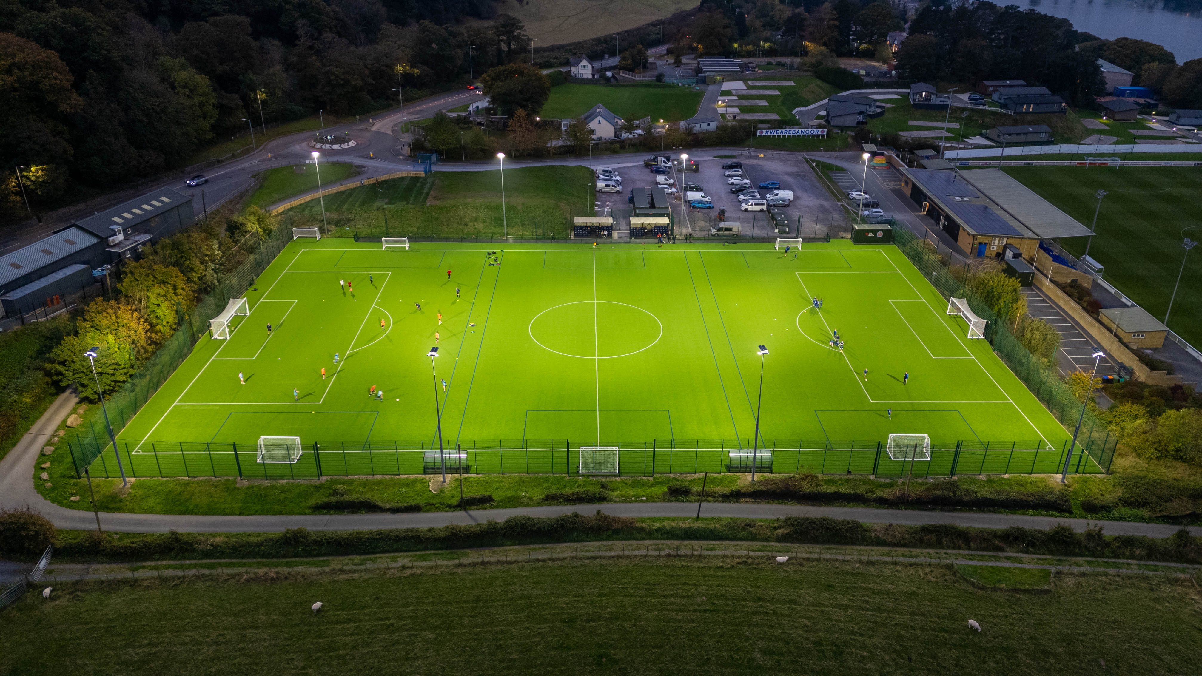 Drone photo of stadium artificial pitch at night with floodlights shining